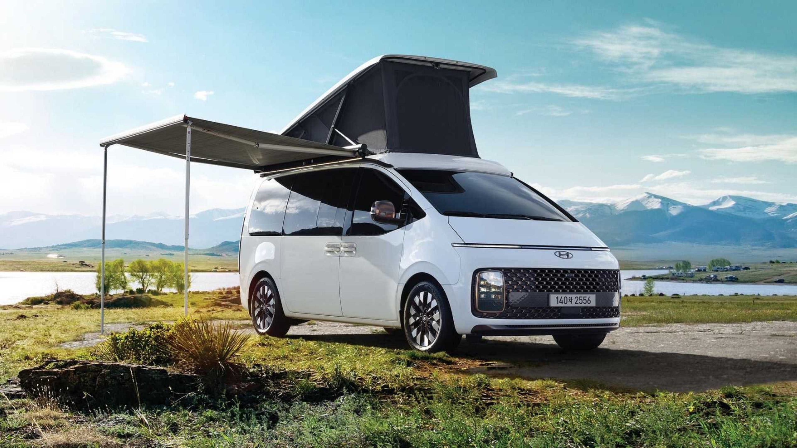 A white 2022 Hyundai Staria Lounge Camper with accessories in a grassy field