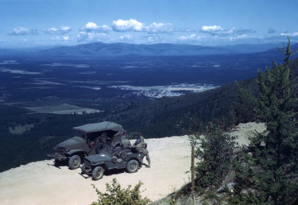 A Willys Jeep and Dodge truck parked on a mountain road during World War Two.