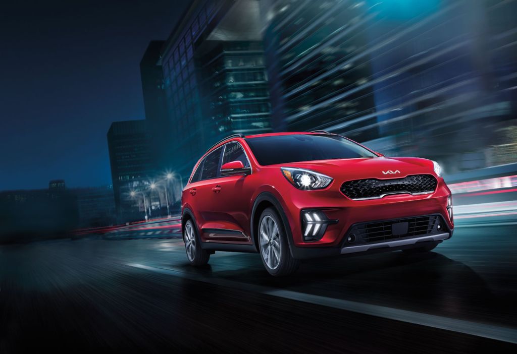 The 2022 Kia Niro hybrid compact SUV in red driving through a city at night