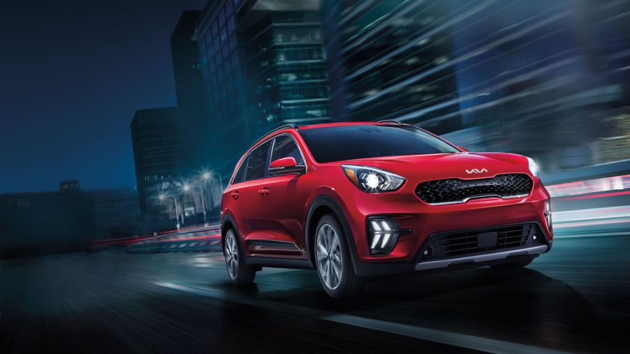 The 2022 Kia Niro hybrid compact SUV in red driving through a city at night