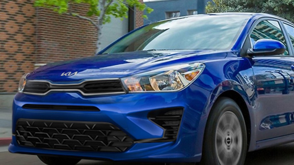 A new 2022 Kia Rio drives down the street with its halogen headlights on
