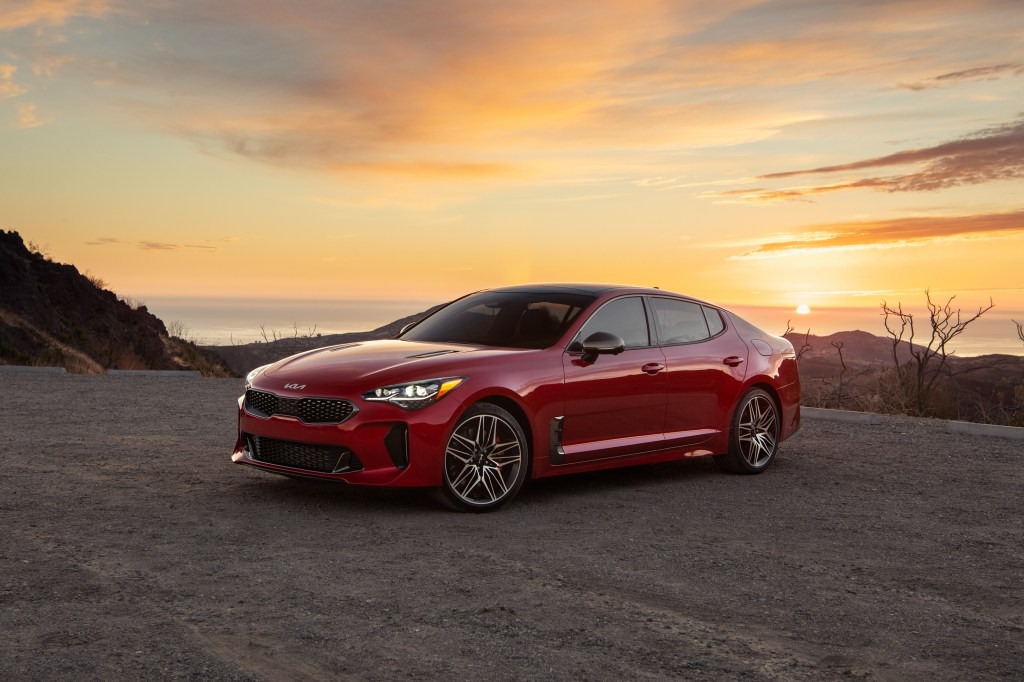 A red 2022 Kia Stinger GT on a mountain road at sunrise/sunset