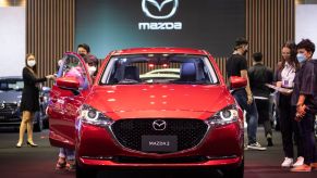 A red 2022 Mazda3 car indoors with the doors open.