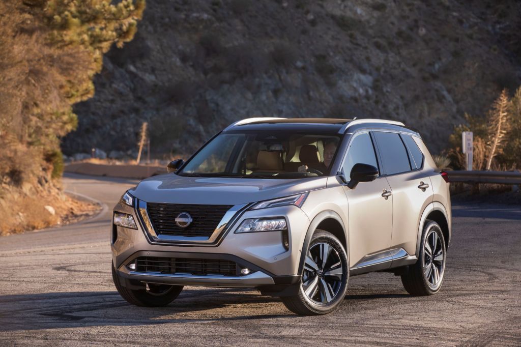 A silver 2022 Nissan Rogue siting in front of background of trees. 