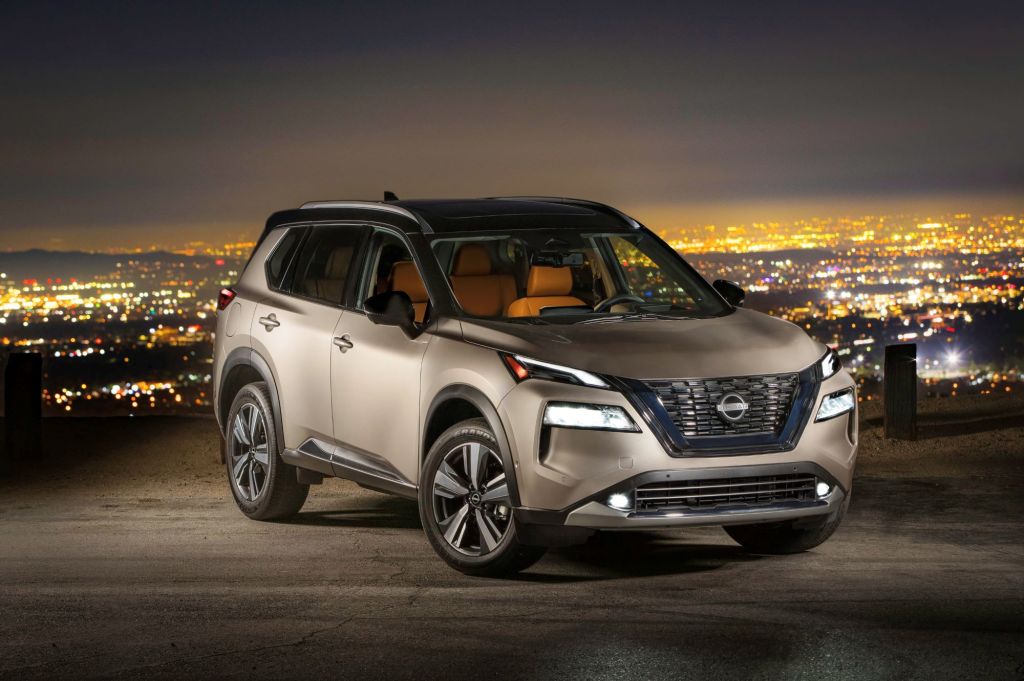 A silver 2022 Nissan Rogue in front of a night time city background.