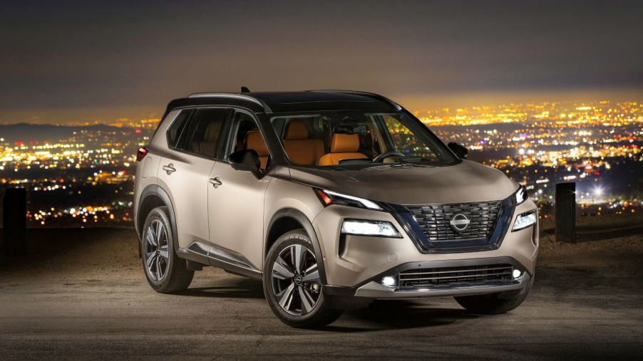 A silver 2022 Nissan Rogue in front of a night time city background.