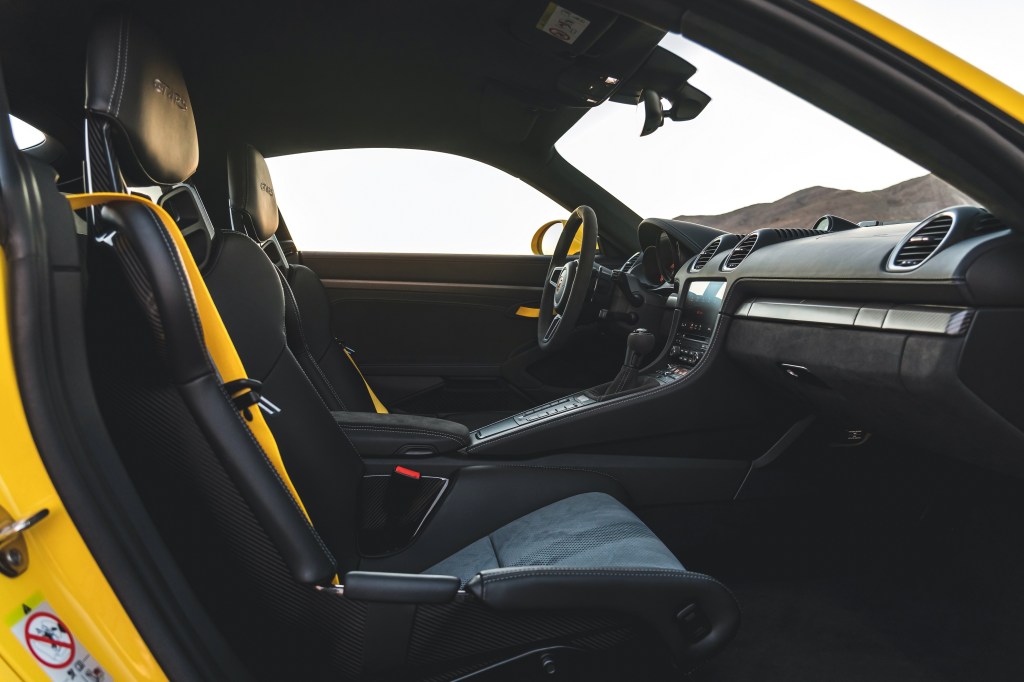 The black sports seats and dashboard of a yellow 2022 Porsche 718 Cayman GT4 RS