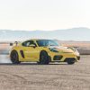 A yellow 2022 Porsche 718 Cayman GT4 RS sliding on a desert racetrack