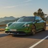 a green 2022 Porsche Taycan Turbo S Cross Turismo is driving along a highway with mountains in the background