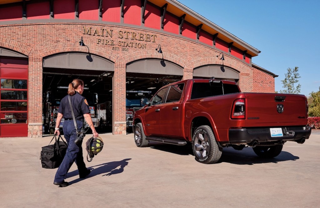 Firefighter walking towards a red pickup truck parked in front of a fire station.