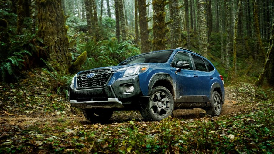 The 2022 Subaru Forester Wilderness compact SUV parked on a leaf-covered path within a forest
