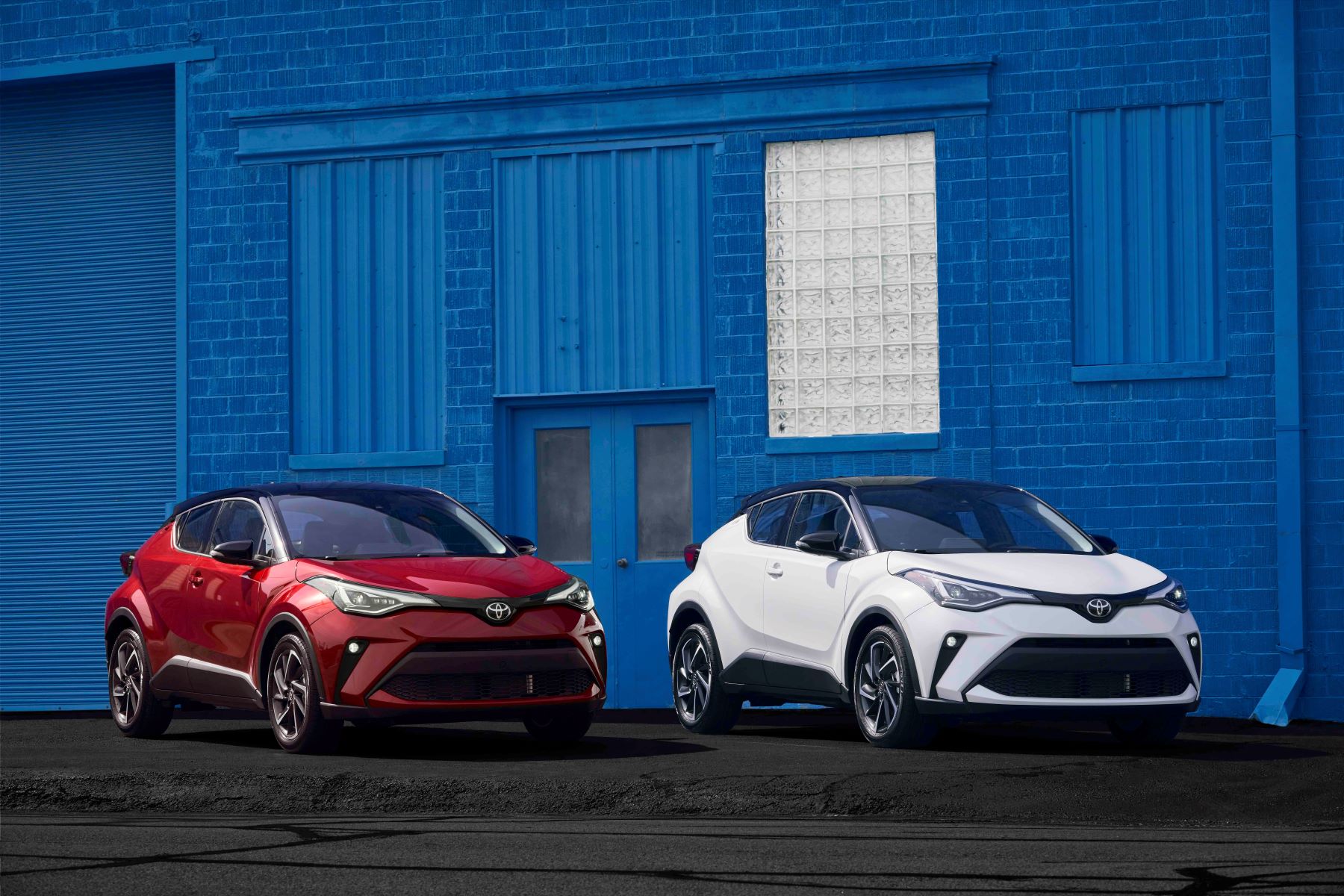 2022 Toyota C-HR models in red and white parked in front of a blue brick building