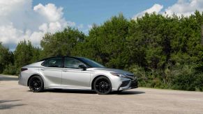 The 2022 Toyota Camry Hybrid XSE midsize sedan in silver with a black roof which gets excellent gas mileage