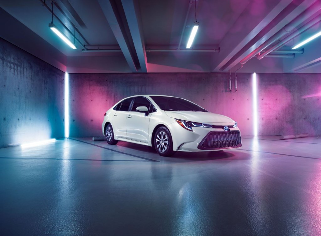 A white 2022 Toyota Corolla Hybrid in a pink and purple lighted indoor environment. 