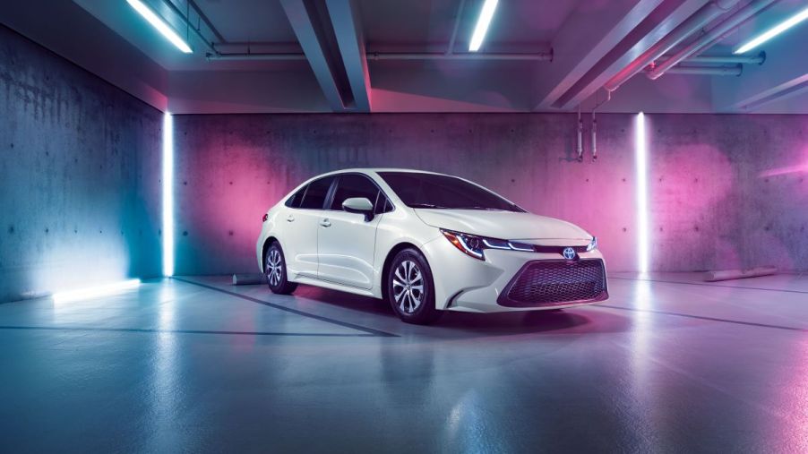 A white 2022 Toyota Corolla Hybrid in a pink and purple lighted indoor environment.