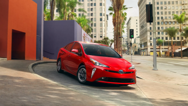 The 2022 Toyota Prius hybrid hatchback model in red driving through a city