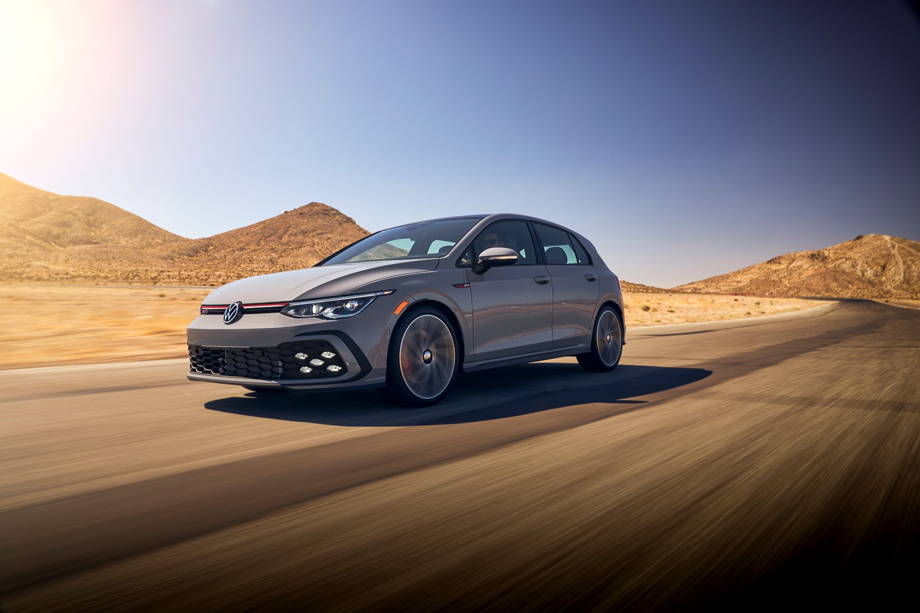 The 2022 Volkswagen Golf GTI hot hatch sporty hatchback model in gray driving through a desert