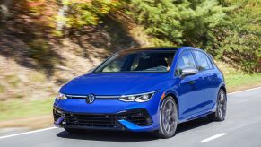 A blue 2022 Volkswagen Golf R driving down a forest canyon road