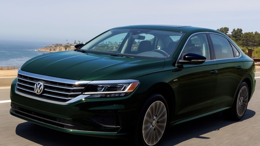a green 2022 Volkswagen Passat drives along a sunny road with the beach and ocean in the back ground