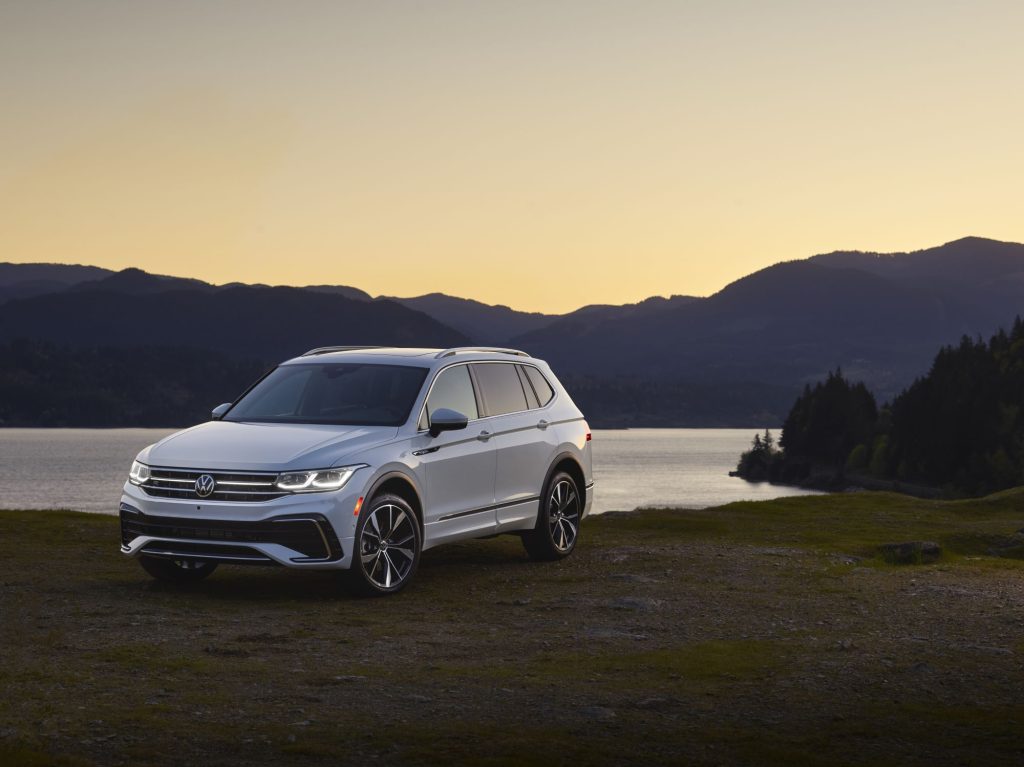 A white 2022 Volkswagen Tiguan parked in front a body of water and mountains. 