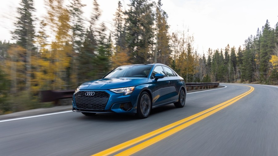 Blue 2022 Audi A3 driving along a well-paved road in the mountains with trees on either side