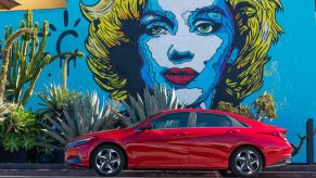 Side view of a red 2022 Hyundai Elantra sedan, one of the best new cars under $20,000, parked in front of a large mural