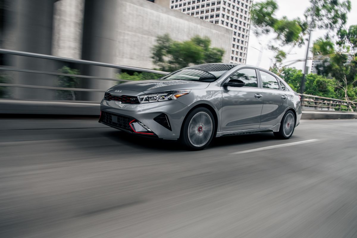 2022 Kia Forte GT-Line in Steel Gray driving along a paved road under a bridge