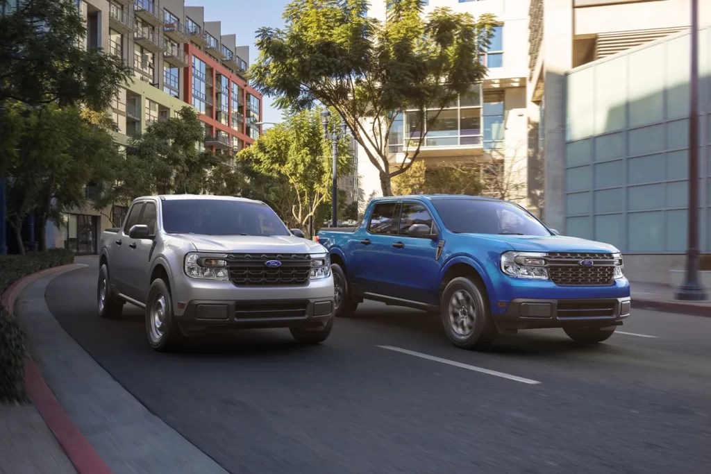 A pair of 2022 Ford Maverick compact trucks navigate an urban environment. 