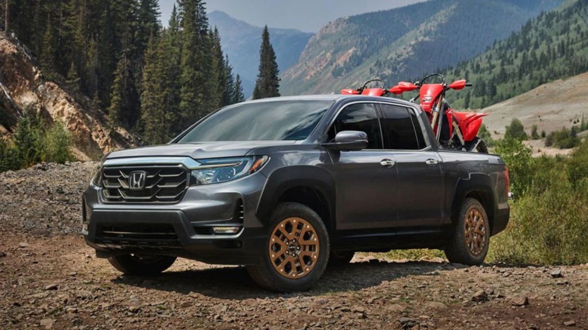 A 2022 Honda Ridgeline hauls a pair of motorbikes in its bed.