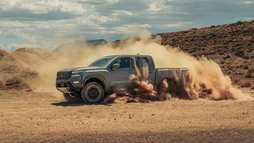 A 2022 Nissan Frontier PRO-4X tears up a desert area, it is not the SV model