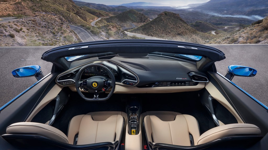 An overhead view of a blue 2023 Ferrari 296 GTS's tan-leather sports seats and black dashboard