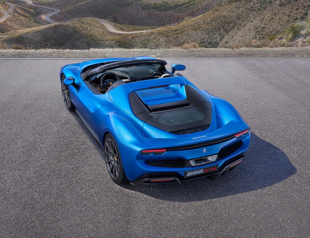 A rear 3/4 overhead view of a blue 2023 Ferrari 296 GTS with its top down in the desert canyons