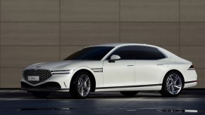 A white 2023 Genesis G90 next to a brown stone wall