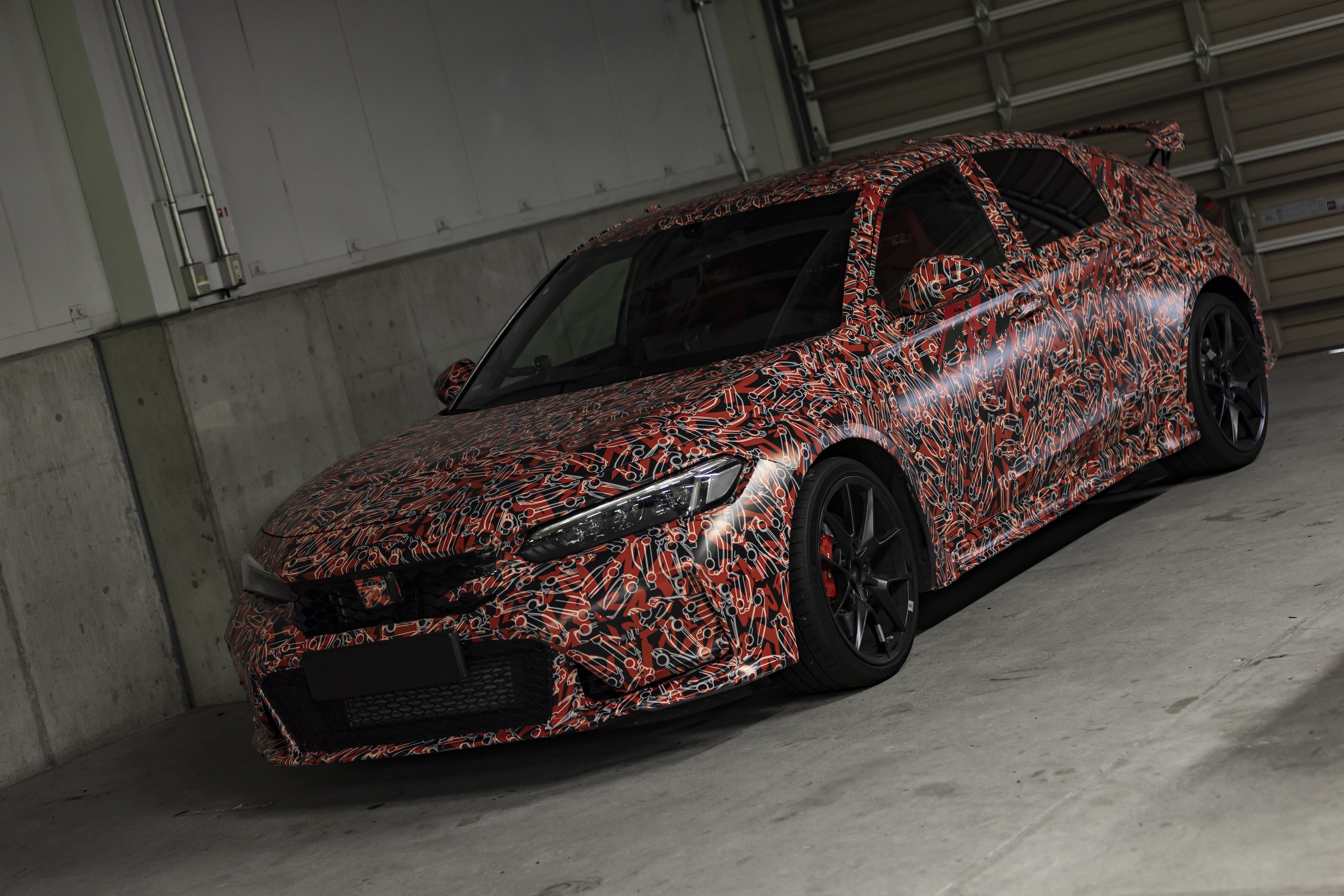 The red-and-white-camouflaged 2023 Honda Civic Type R prototype in a garage
