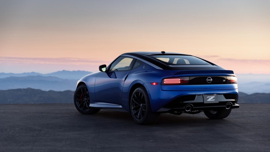 The rear 3/4 view of a blue 2023 Nissan Z overlooking a city at sunset