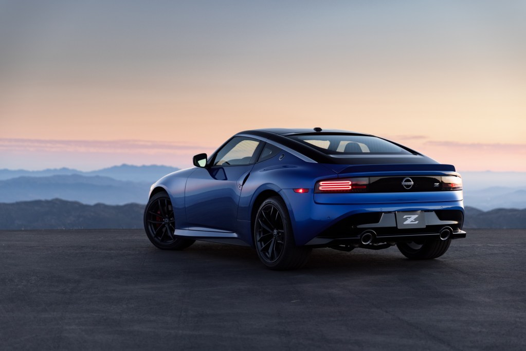 The rear 3/4 view of a blue 2023 Nissan Z overlooking a city at sunset