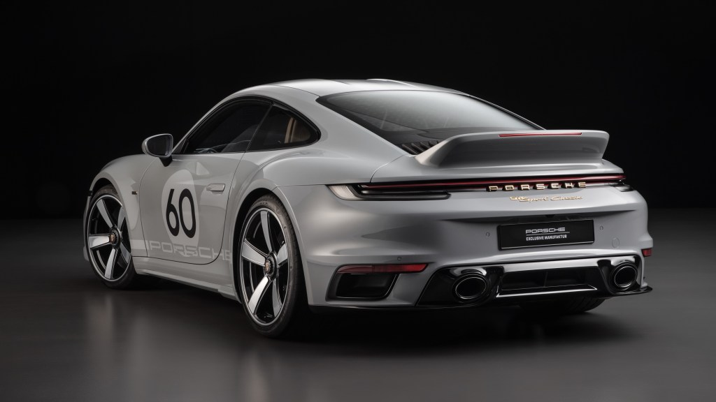 The rear 3/4 view of a gray-and-silver-striped 2023 Porsche 911 Sport Classic in a black studio