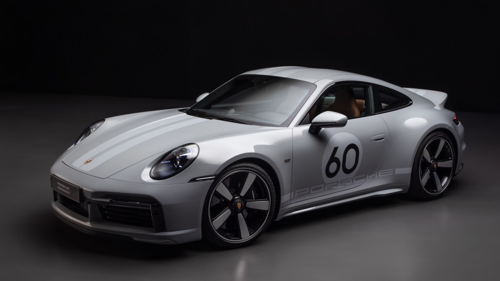 A gray-and-silver-striped 2023 Porsche 911 Sport Classic in a black studio