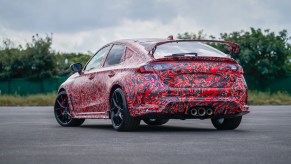 Rear view of a heavily camouflaged 2023 Honda Civic Type R sedan with a big rear wing spoiler