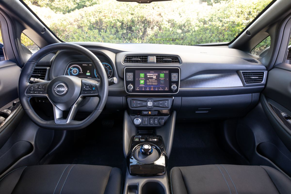 Black interior of the 2023 Nissan LEAF electric vehicle, with contrast piping on the seats and a wide touchscreen infotainment system
