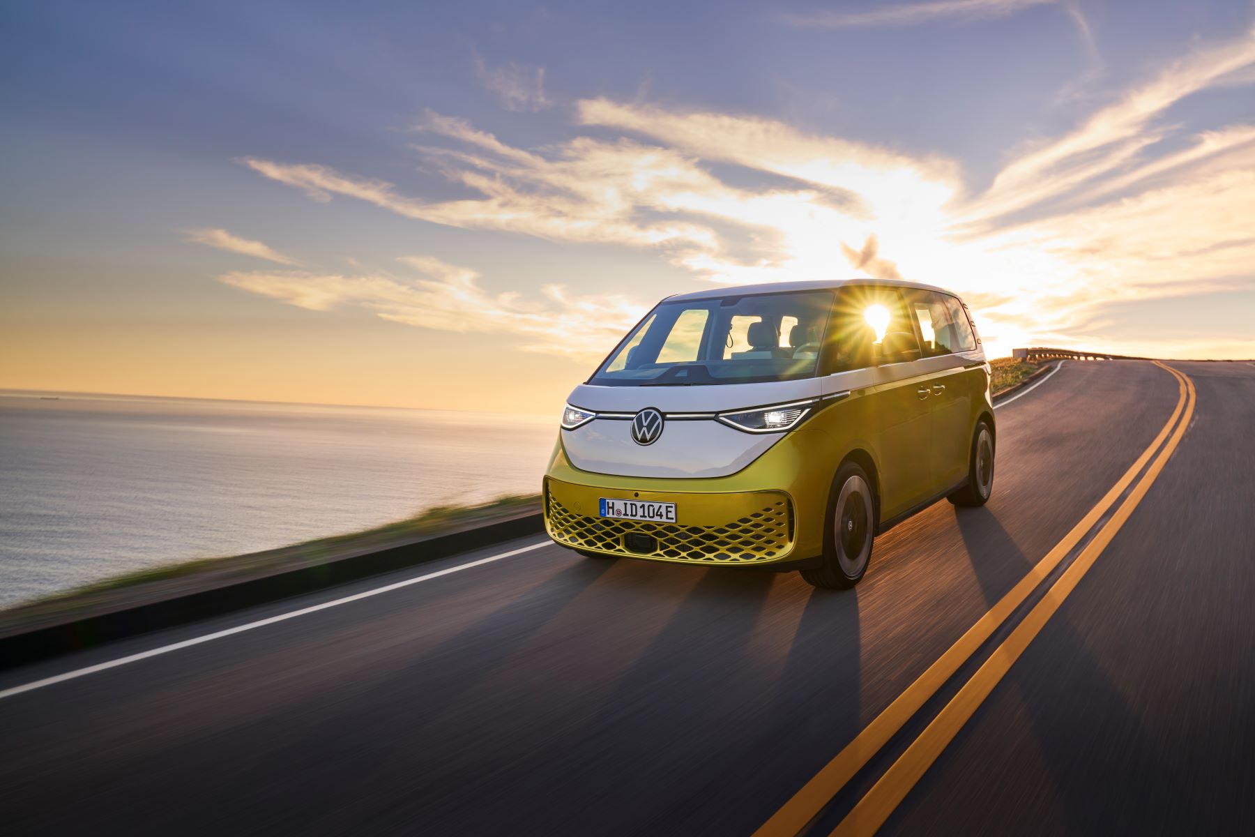 2024 Volkswagen ID. Buzz all-electric van with a yellow and white color option driving down a highway with a sunset