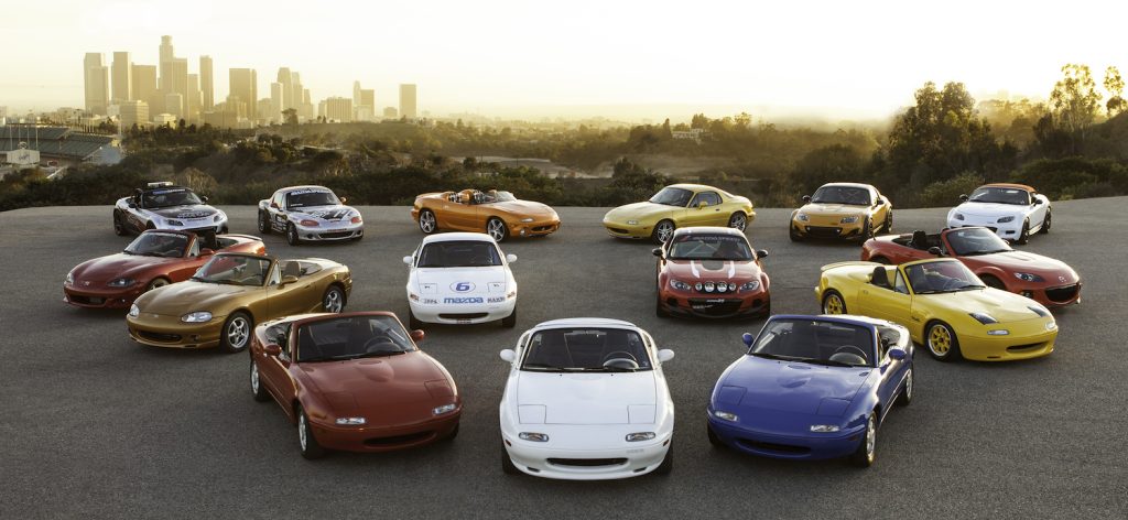 A parking lot full of various MX-5 internal combustion Miatas from roadster history.