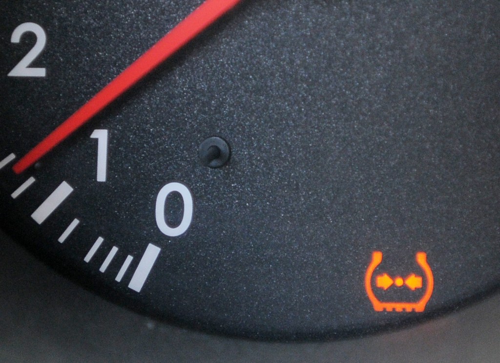 A black Lexus dial with an illuminated TPMS light and a red needle