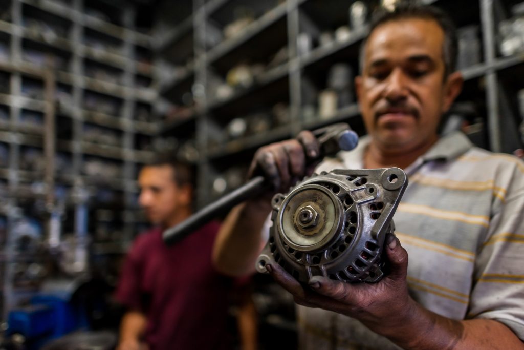 A Columbian car mechanic in Barrio Triste holds up an alternator