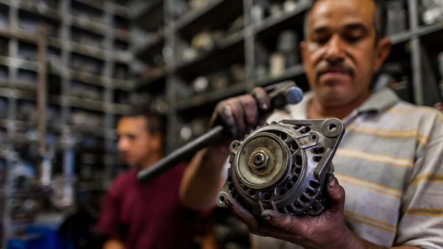 A Columbian car mechanic in Barrio Triste holds up an alternator