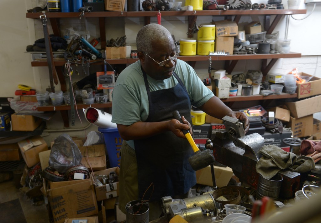 A mechanic disassembling a car alternator by hand in his workshop
