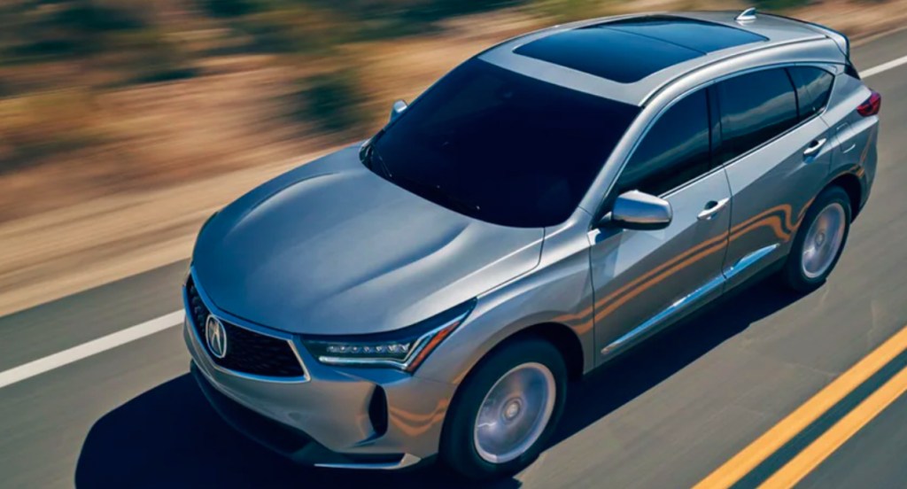 A silver 2022 Acura RDX small SUV is driving on the road.