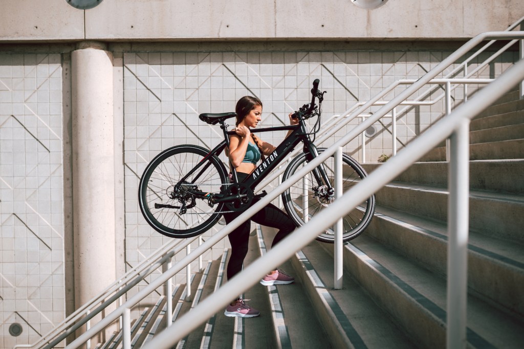 A rider carries the Aventon Soltera up stairs