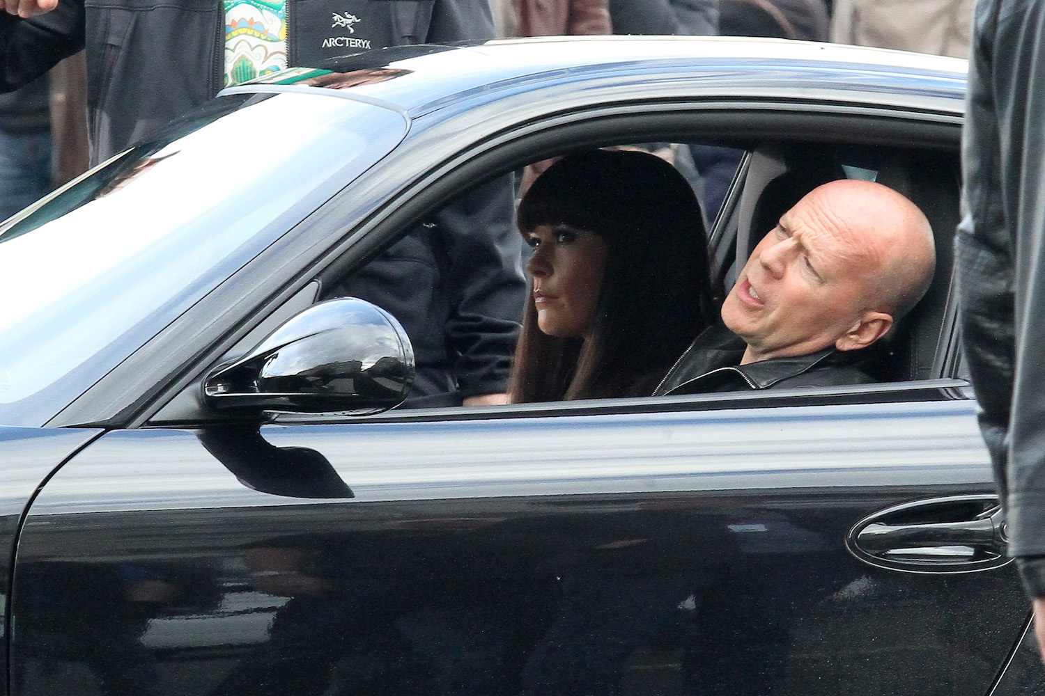 Bruce Willis filming a movie scene, driving a porsche sports car.