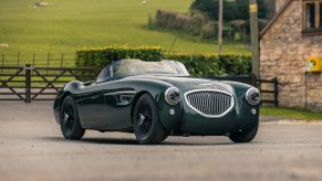 A dark-green Caton Austin-Healey 100 restomod on a British countryside track